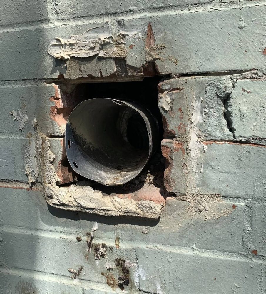 Exterior dryer vent hood and wall penetration, before the work