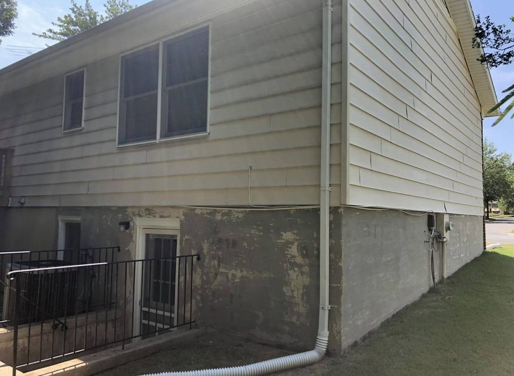Exterior foundation and siding repainted on a residential home, before the work