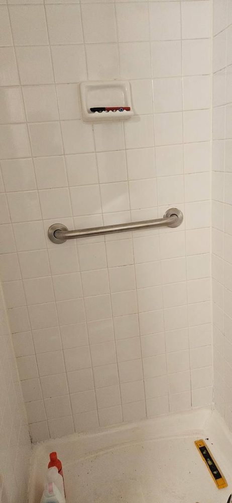 Bathroom grab bar anchored to the wall beside a tub and shower