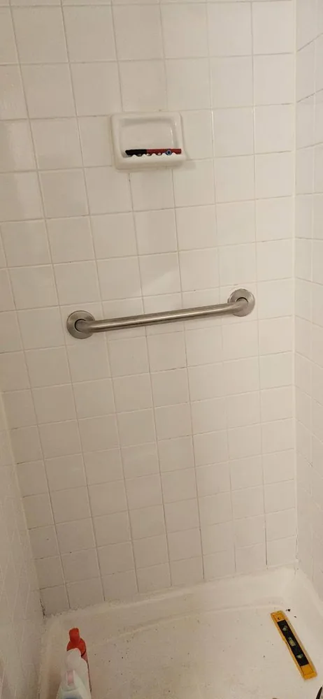 Stainless grab bar mounted level on a tiled bathroom wall