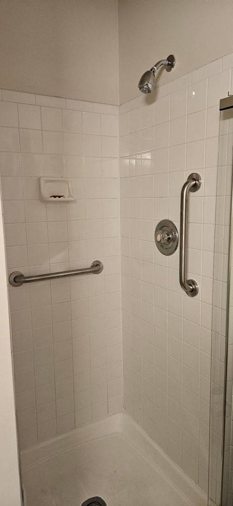 Bathroom grab bar anchored to the wall beside a tub and shower