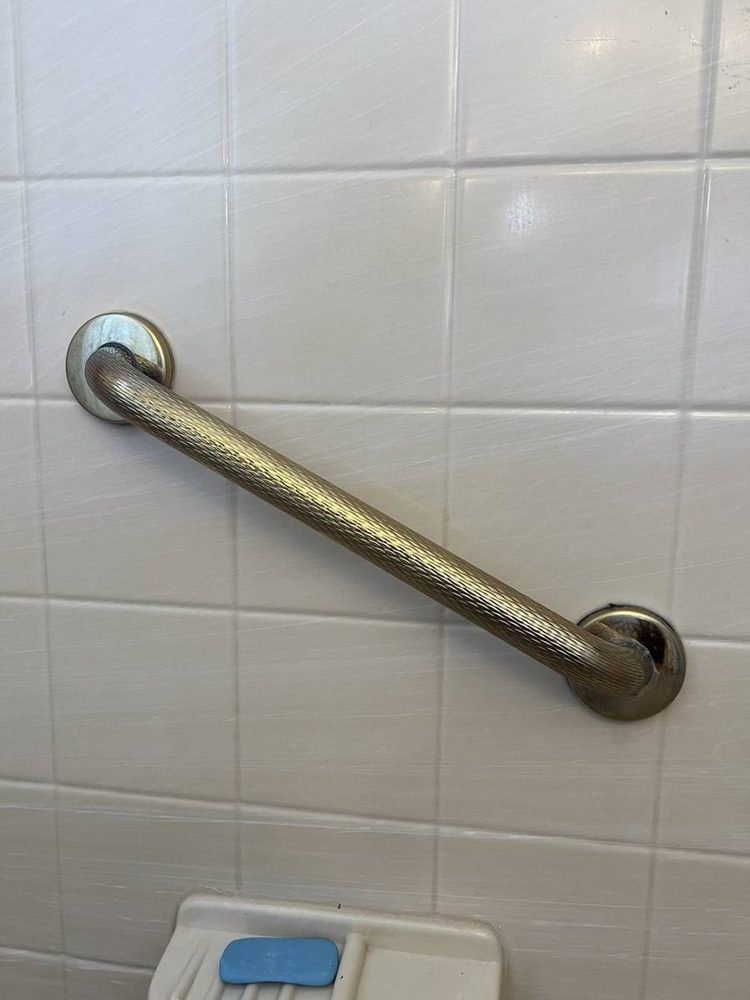 Bathroom grab bar anchored to the wall beside a tub and shower