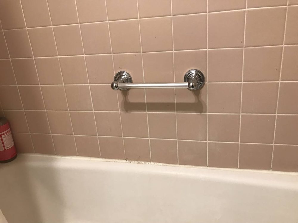 Bathroom grab bar anchored to the wall beside a tub and shower
