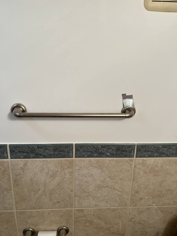 Bathroom grab bar anchored to the wall beside a tub and shower